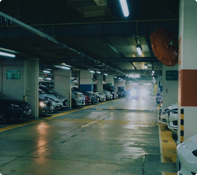 Parking couvert avec voitures stationnées, éclairage intérieur et allées sécurisées chez Bela Park